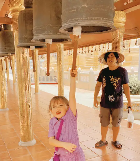 Little girl ringing the bell at one of the most family friendly temples in Bangkok