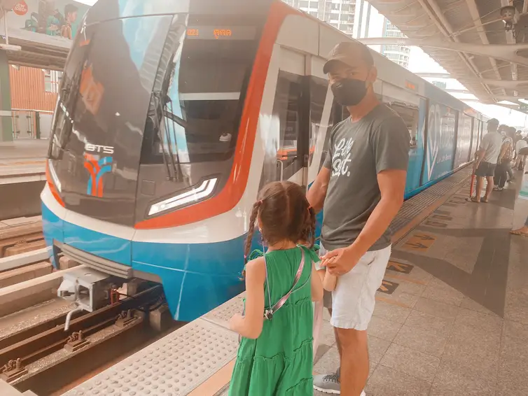 Dad and daughter riding BTS Sky Train in Bangkok